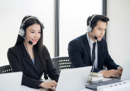 Operator in headphones with microphone consulting client on laptop in customer support service.